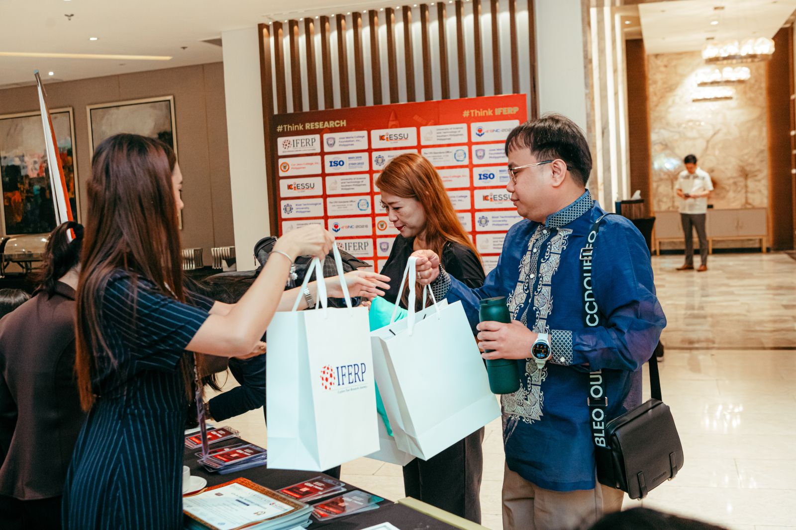 A delegate collecting an IFERP conference kit at the registration desk