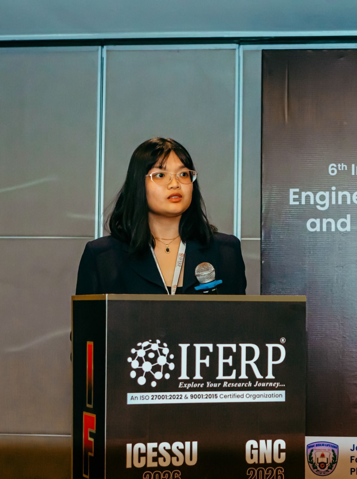 A presenter delivering her paper at the lectern during a technical session